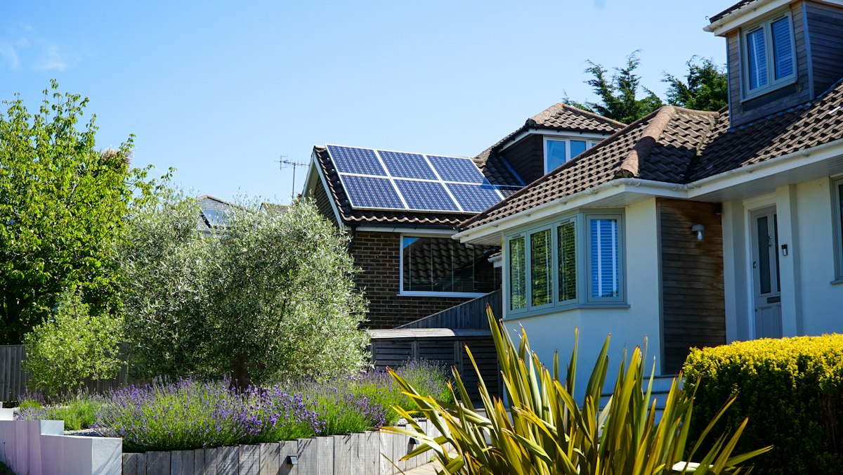 Solar panels on the roof of a house in the UK, with a lavender garden in front